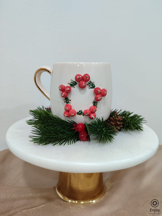 Handmade winterberry mug with gold handle on a pine branch with a white bacground