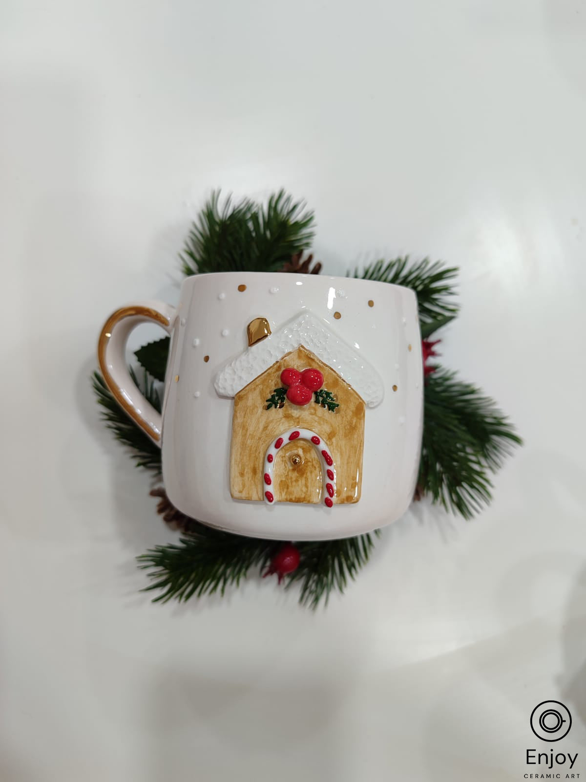 A chic white mug adorned with 3D gingerbread house design, resting on a green pine branch
