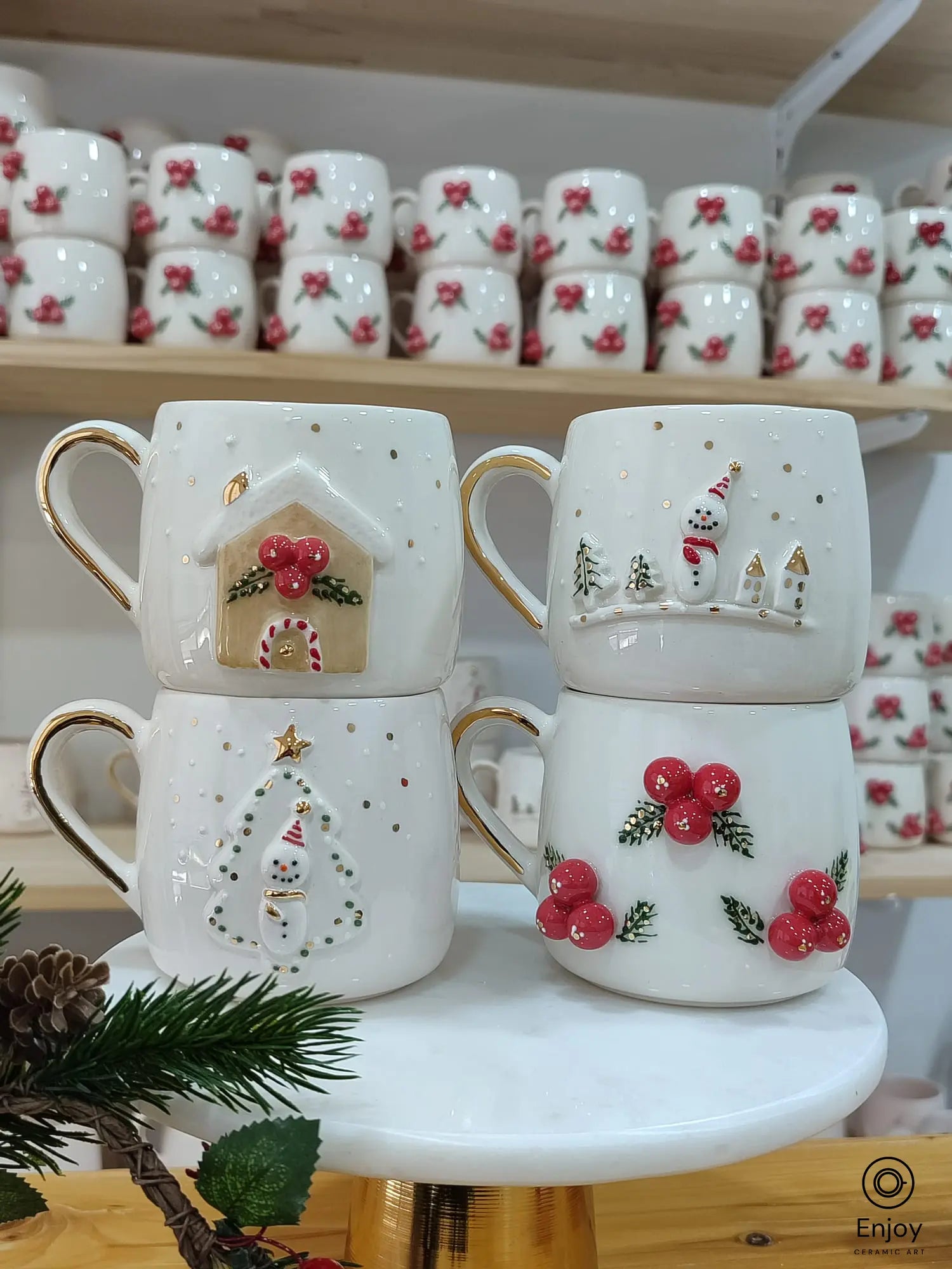 Handcrafted Christmas-themed ceramic mug set featuring four designs: a snowman, Christmas tree, gingerbread house, and winter berries, all with elegant gold handles.