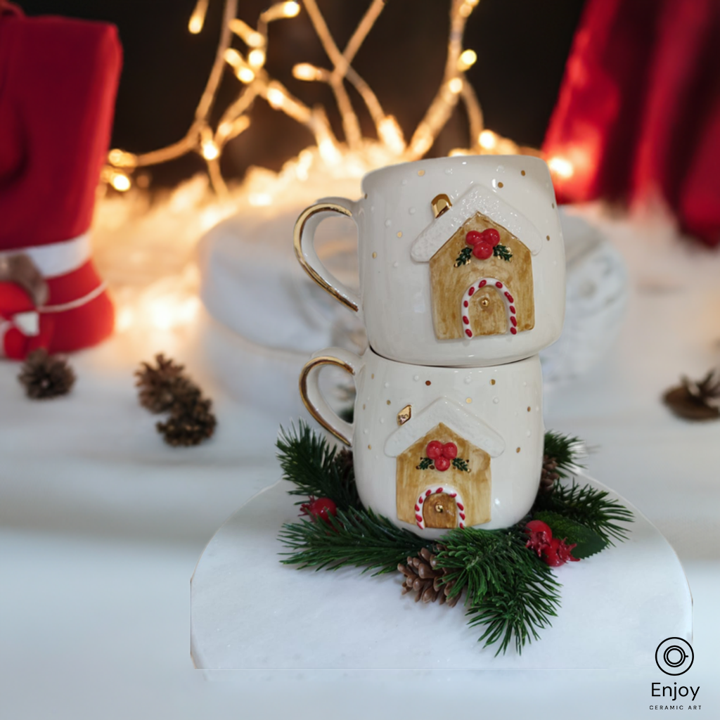 Two stacked ceramic mugs featuring a festive gingerbread house design, surrounded by pine branches and pinecones, glowing against a backdrop of twinkling holiday lights.