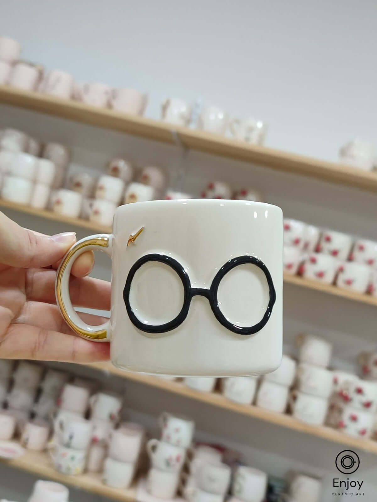 Handmade ceramic mug inspired by a beloved wizard, featuring iconic round glasses and a lightning bolt in delicate gold. The subtle, minimalist design brings a touch of magic to every sip.