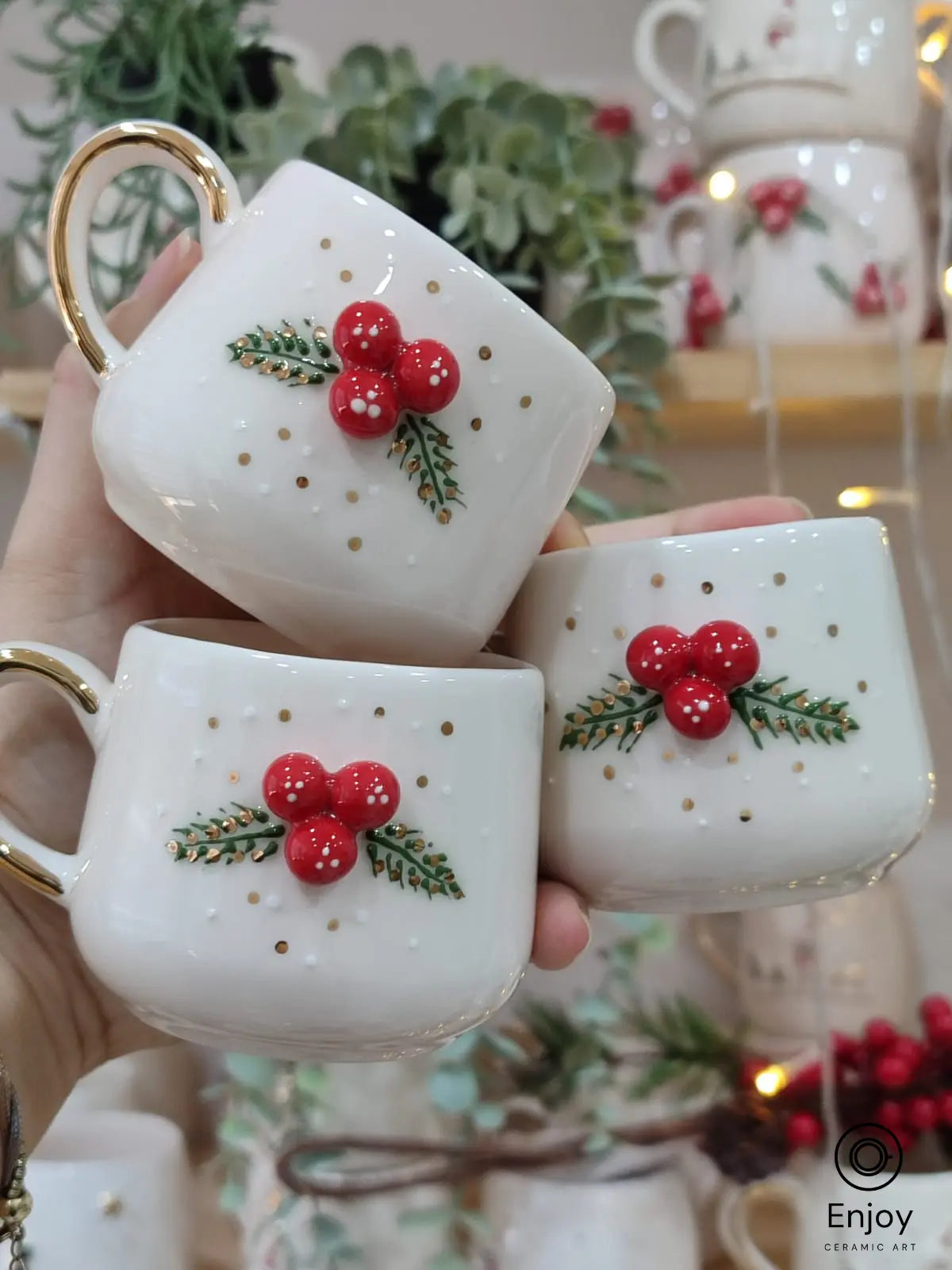 Handmade ceramic mugs with festive holly berry and gold accents, featuring elegant gold handles—perfect for Christmas and holiday gifts.