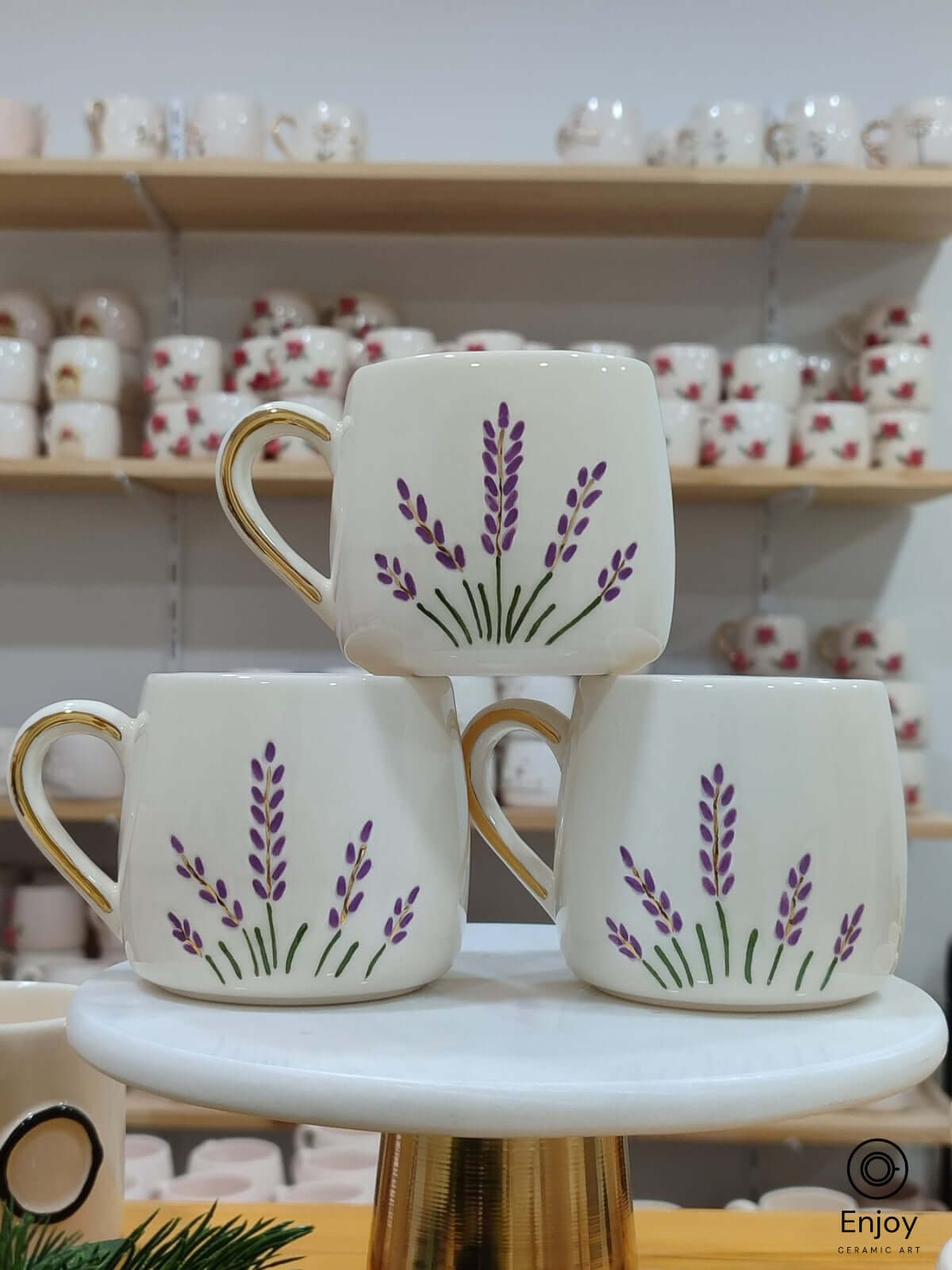 A trio of handcrafted ceramic mugs adorned with delicate lavender sprigs, each topped with a touch of gold on the handle, perfect for bringing a hint of nature’s calm to your coffee ritual.