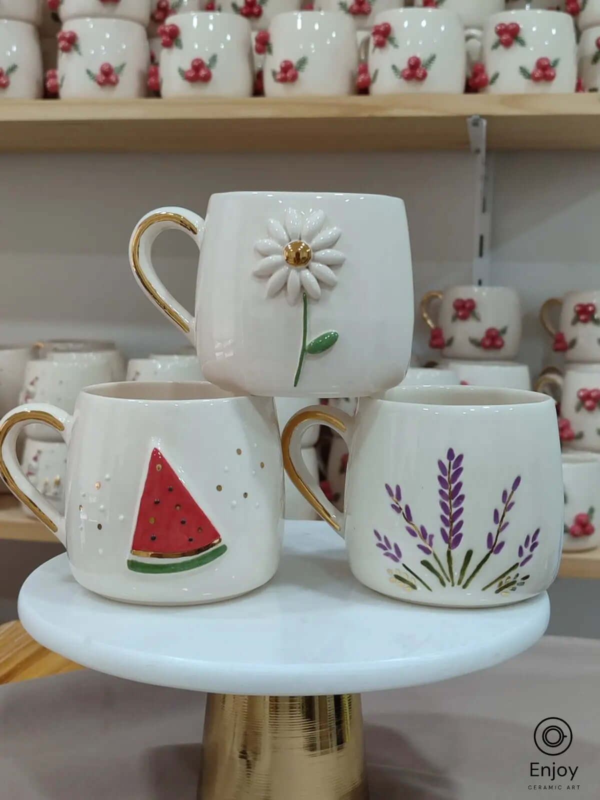 Set of three handmade ceramic mugs featuring daisy, watermelon, and lavender designs with gold handles