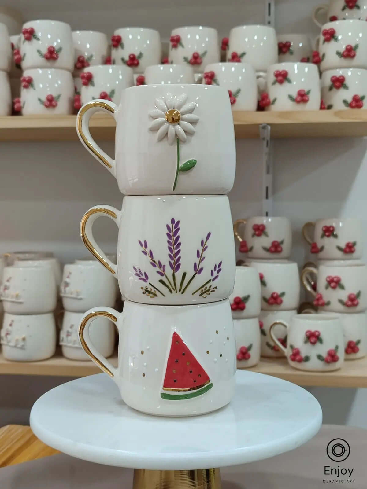 Set of three handmade ceramic mugs featuring daisy, watermelon, and lavender designs with gold handles