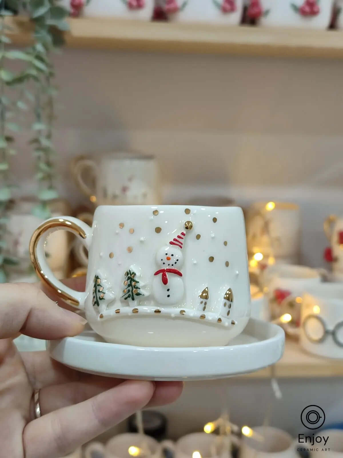 Snowman-themed handmade ceramic espresso cup with gold accents and matching saucer. Perfect for festive coffee moments.