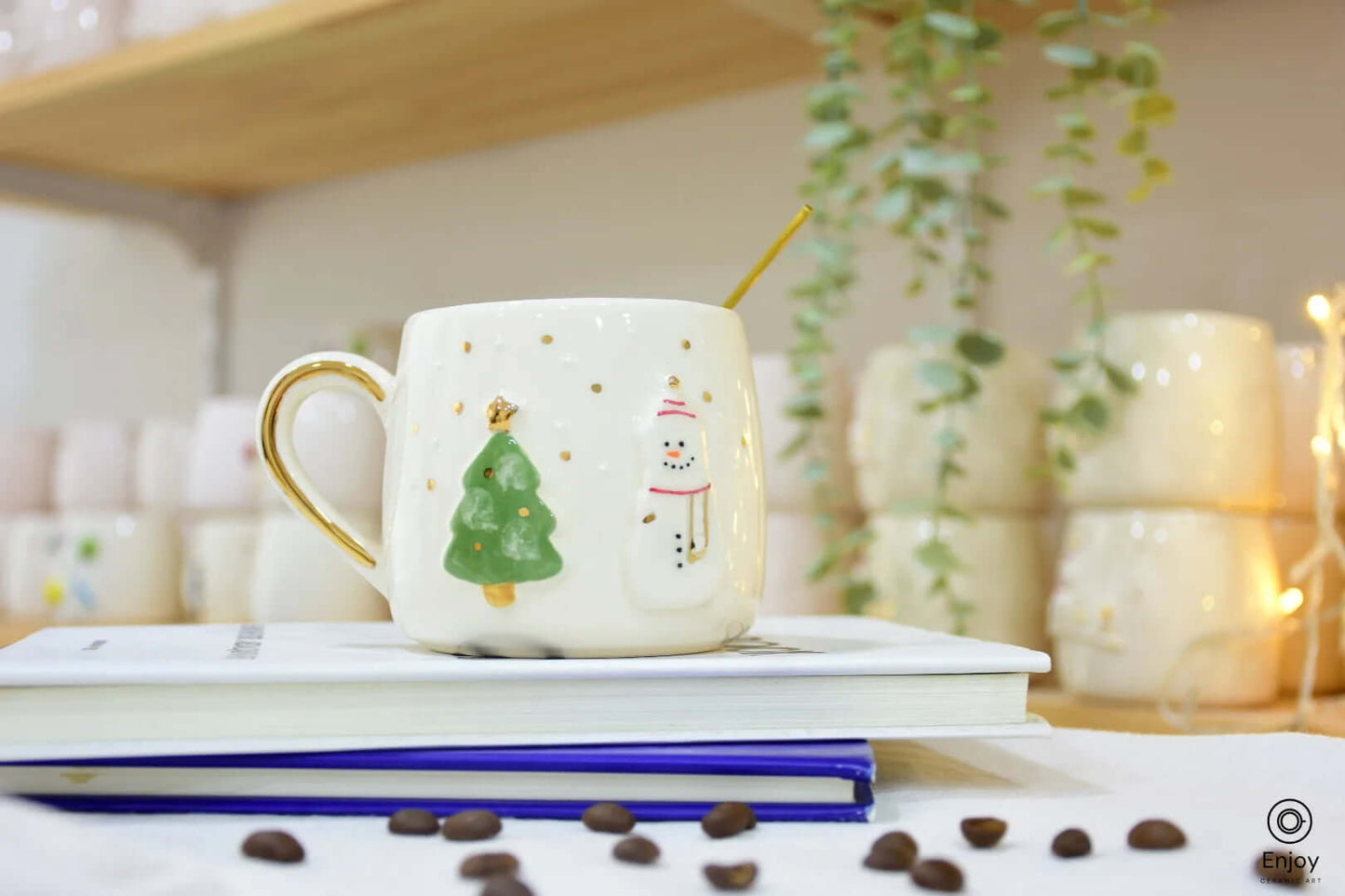 A ceramic mug with festive details including a green Christmas tree and a smiling snowman, embellished with gold accents and a golden handle.