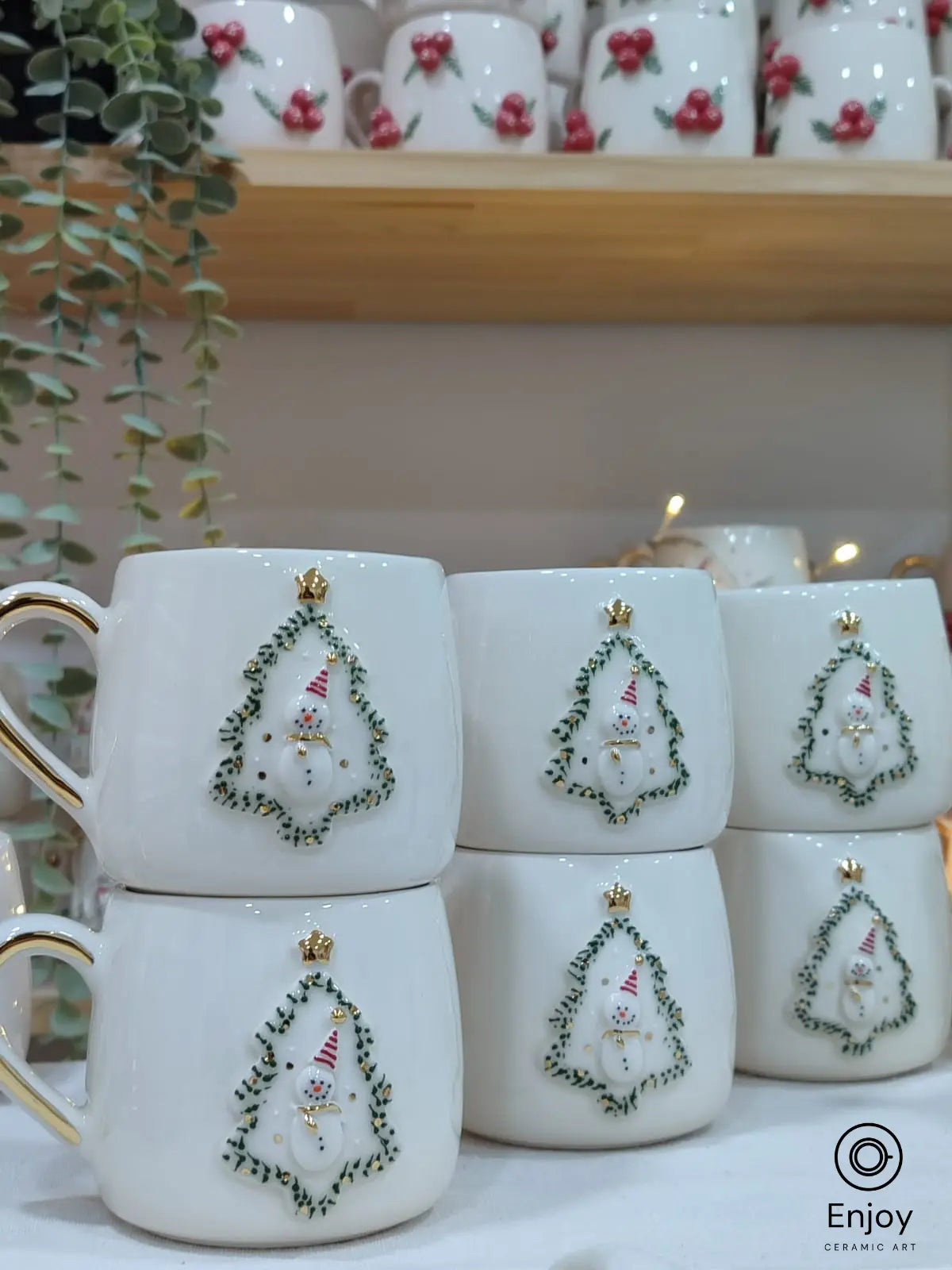 Stacked handmade ceramic mugs showcasing a snowman in a Christmas tree frame. Festive, elegant, and crafted with love for the holidays! 🎄☕