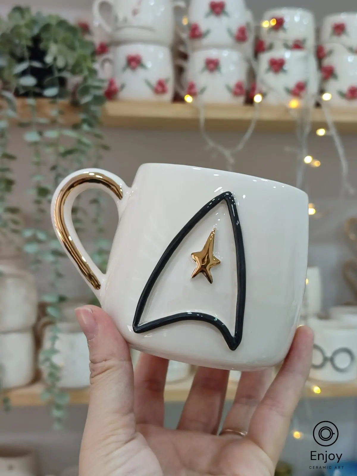 Handmade ceramic mug with a black and gold Star Trek-inspired emblem and a gold handle, perfect for sci-fi fans and collectors.