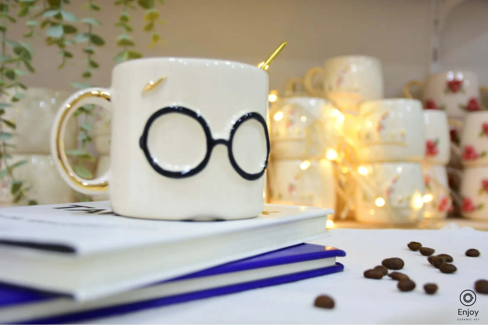 A ceramic mug with black round glasses and a gold lightning bolt detail, resting on stacked books with scattered coffee beans, evoking a magical theme.